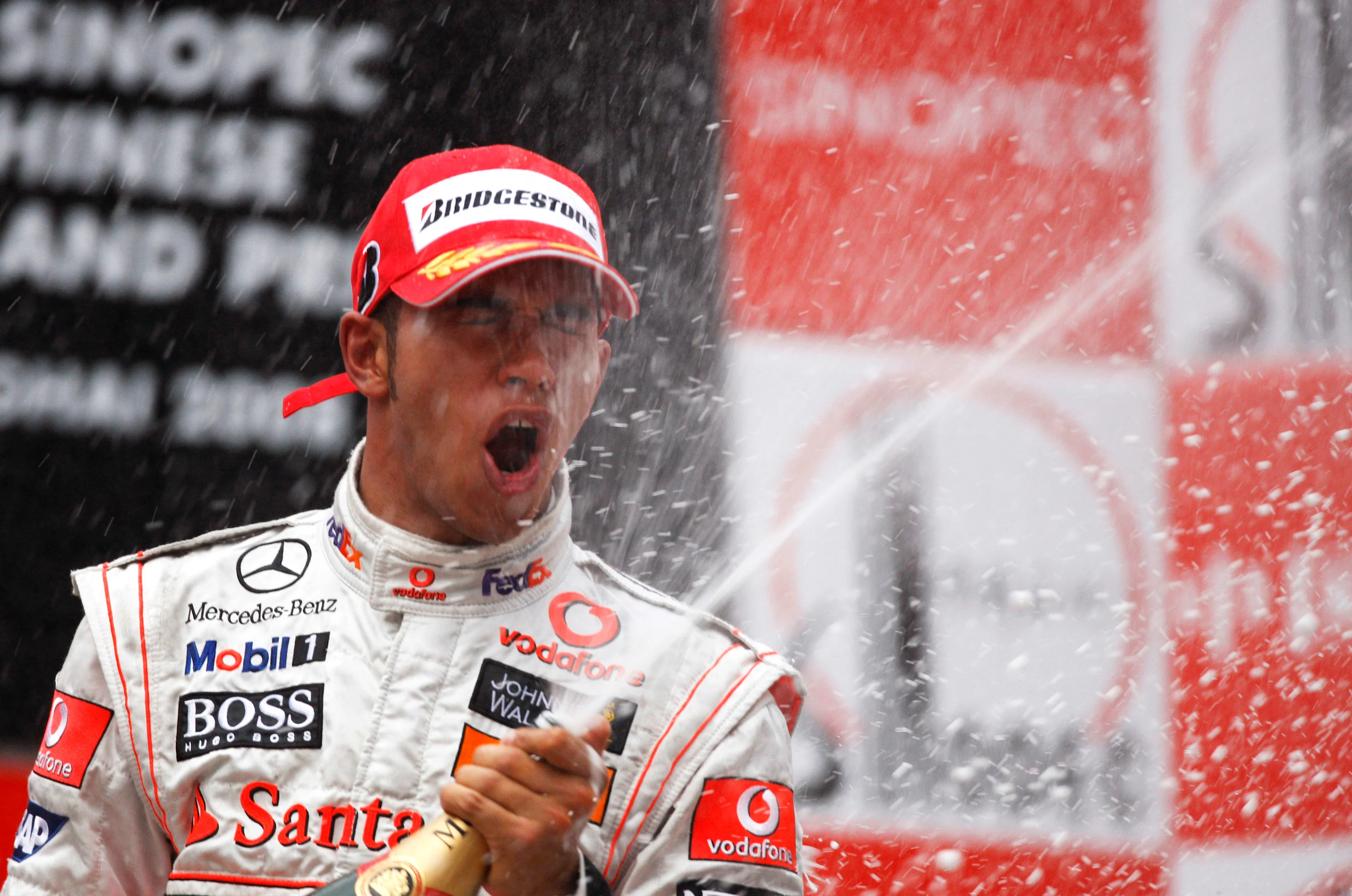 British McLaren Formula One driver Lewis Hamilton celebrates on the winners podium by spraying